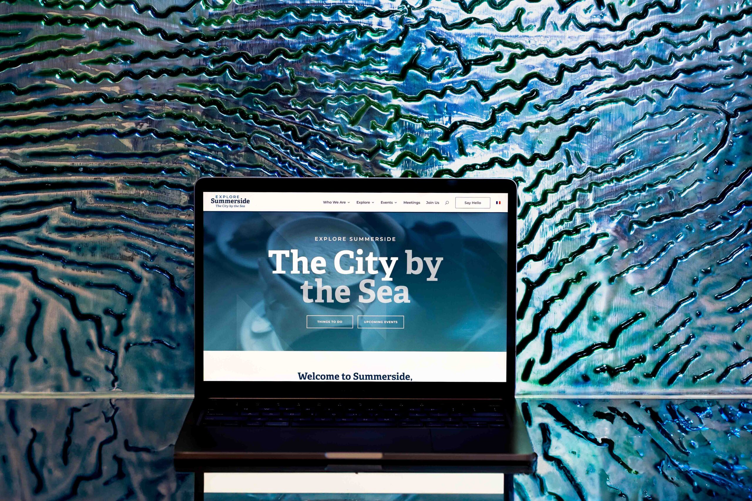 Lake Design Website Design, Photography, Videography, Branding in Prince Edward Island, Toronto and Victoria-5 Explore Summerside website homepage shown on a laptop in front of a wavy blue glass backdrop