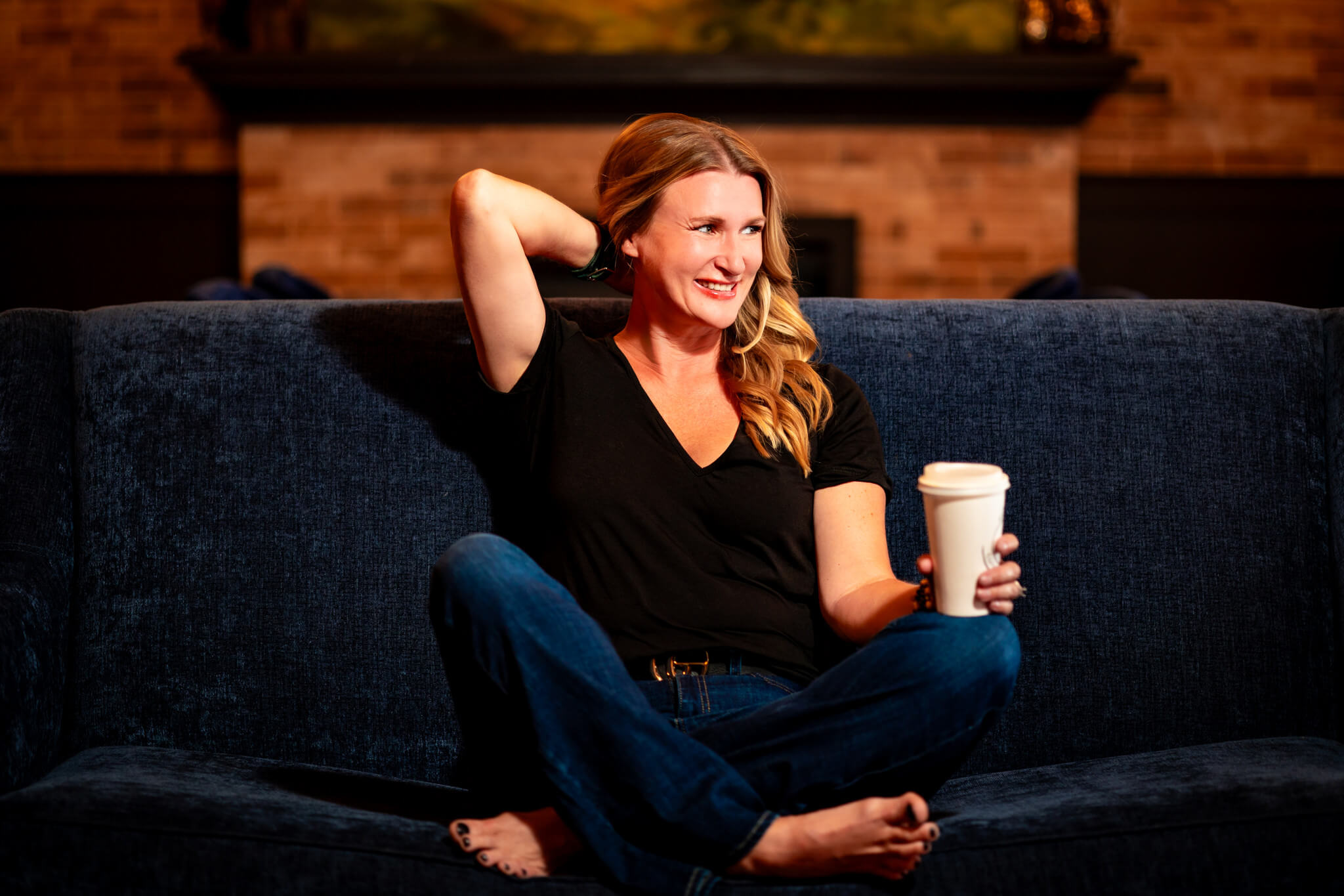 Callie Croken, a life and business coach, relaxing with a coffee on a couch during her branding photoshoot with Lake Design.