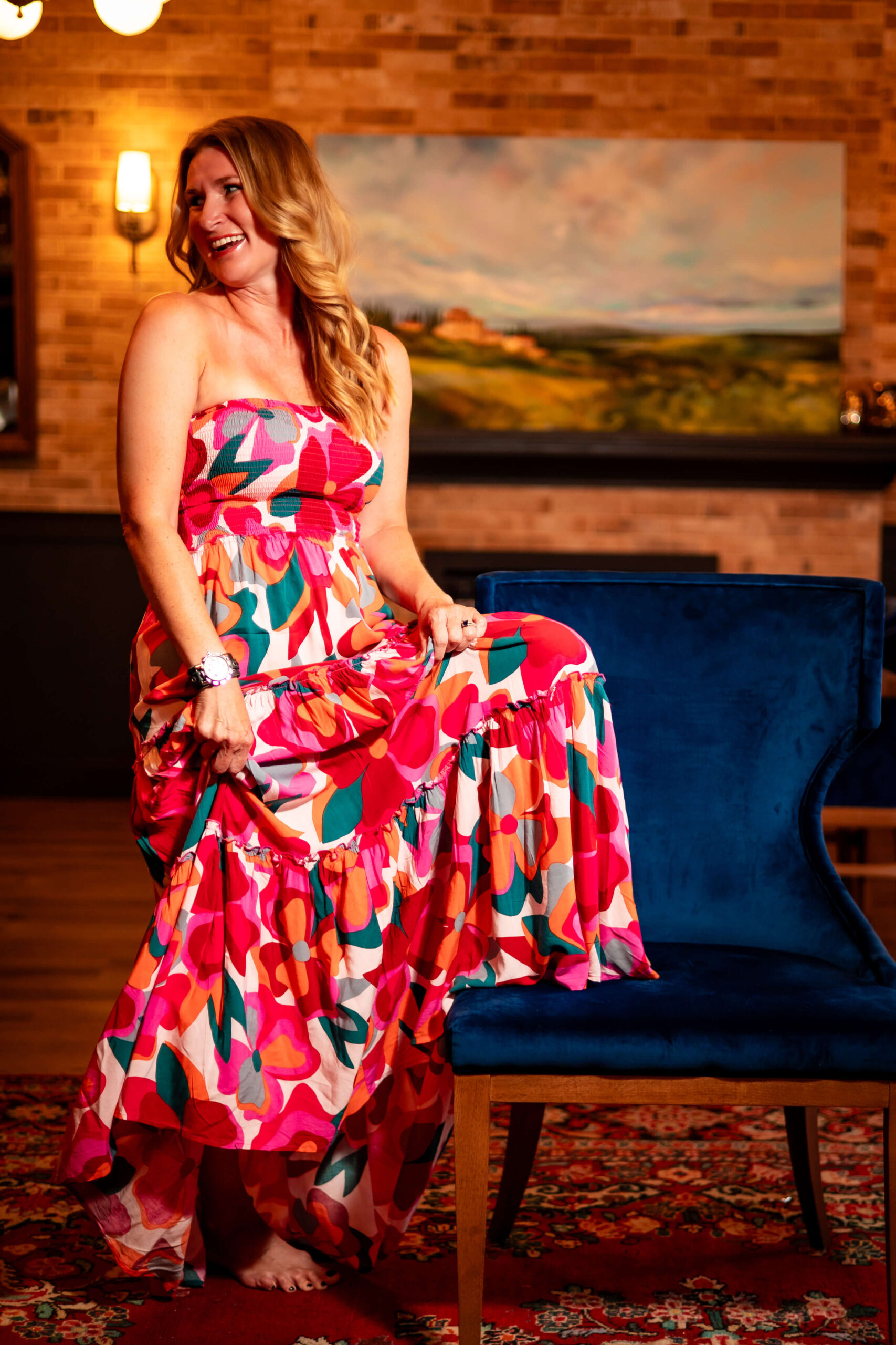 Elegant female entrepreneur laughing in a vibrant dress during a branding photoshoot.