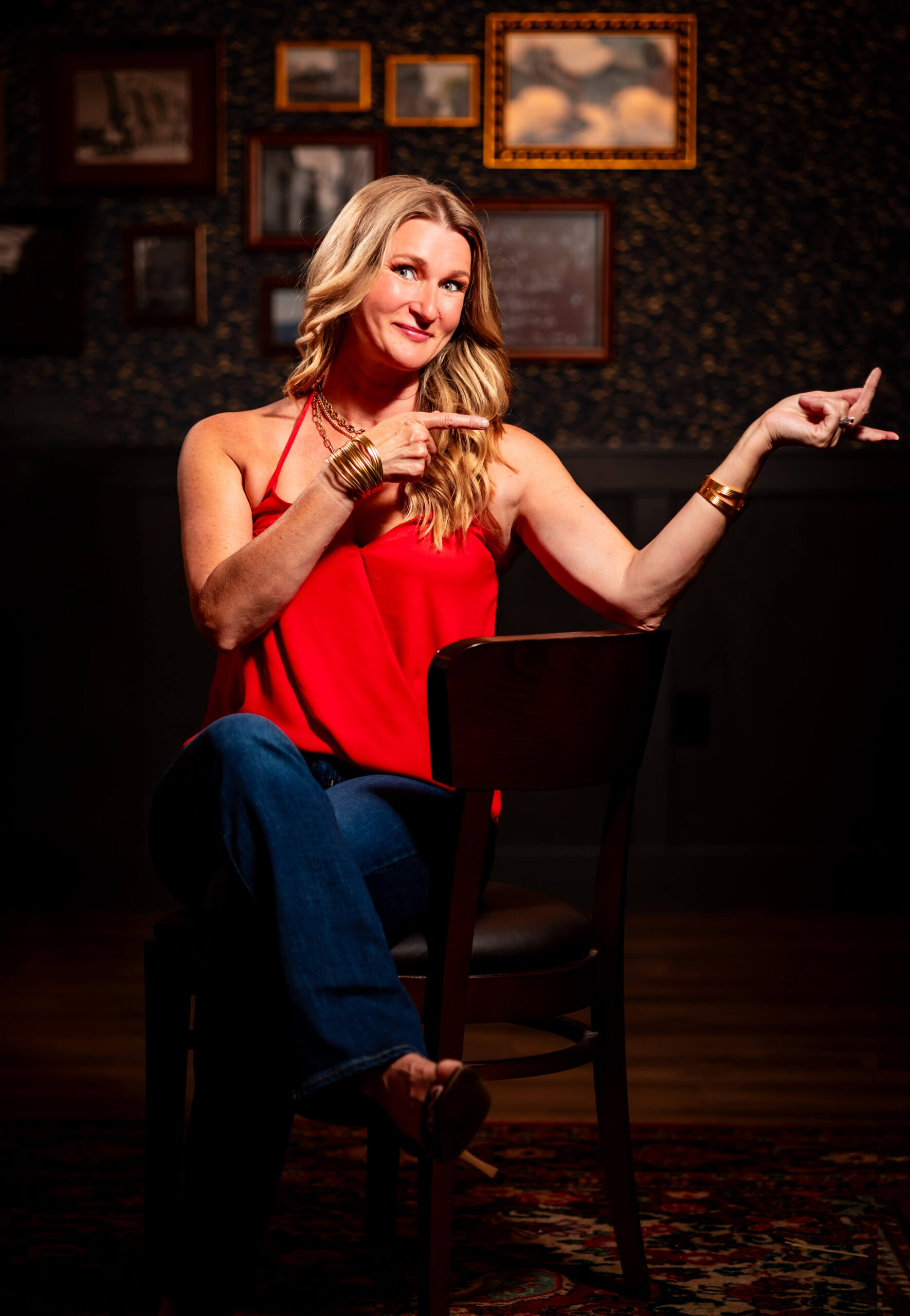 Callie Croken, a life and business coach, confidently posing on a chair in front of unique wall frames during her branding photoshoot with Lake Design.